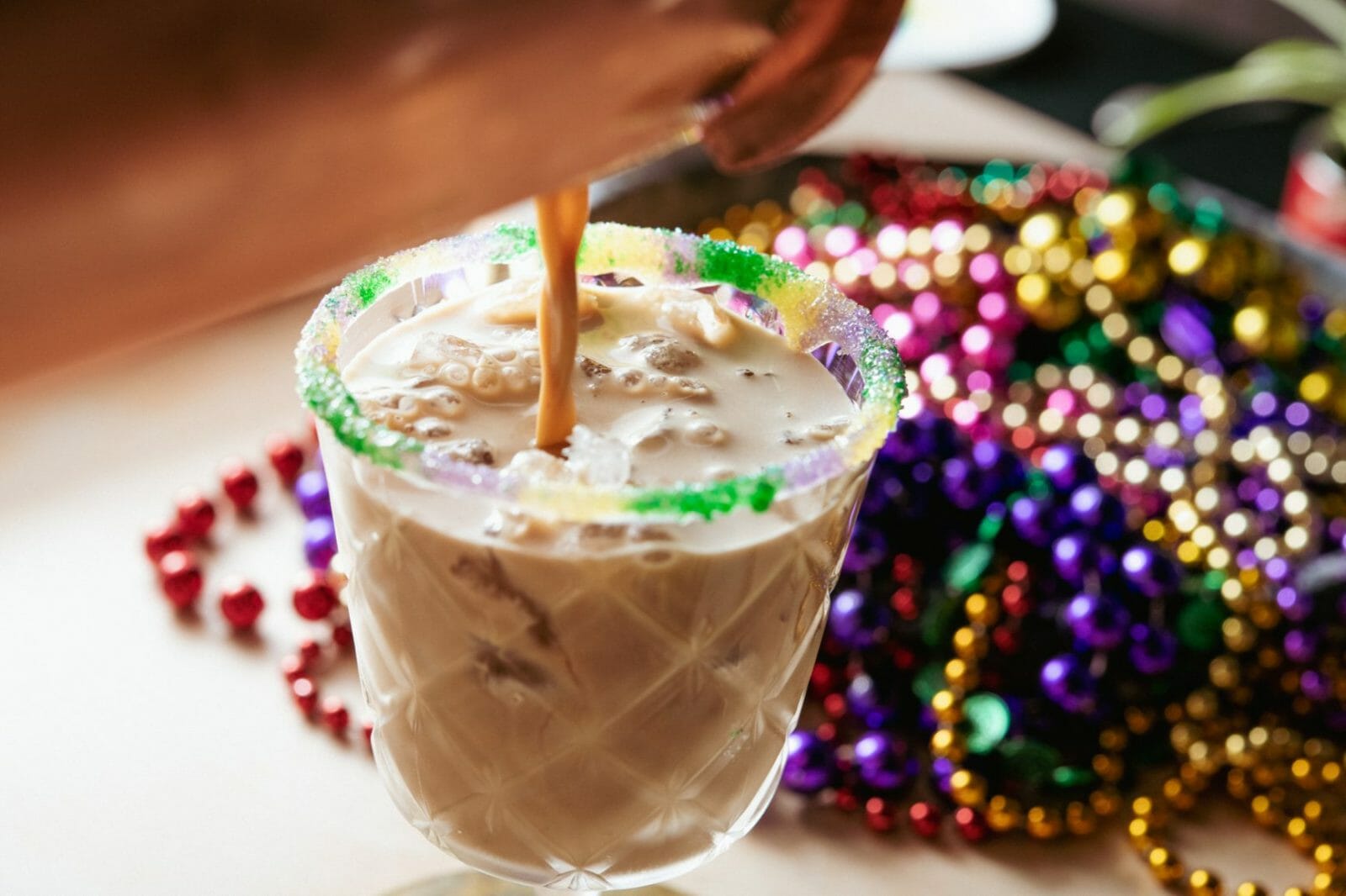 festive Mardi Gras cocktail with beads in background