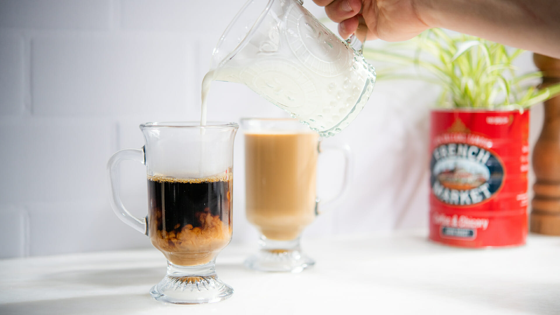 Milk being poured into a glass mug of French Market Coffee