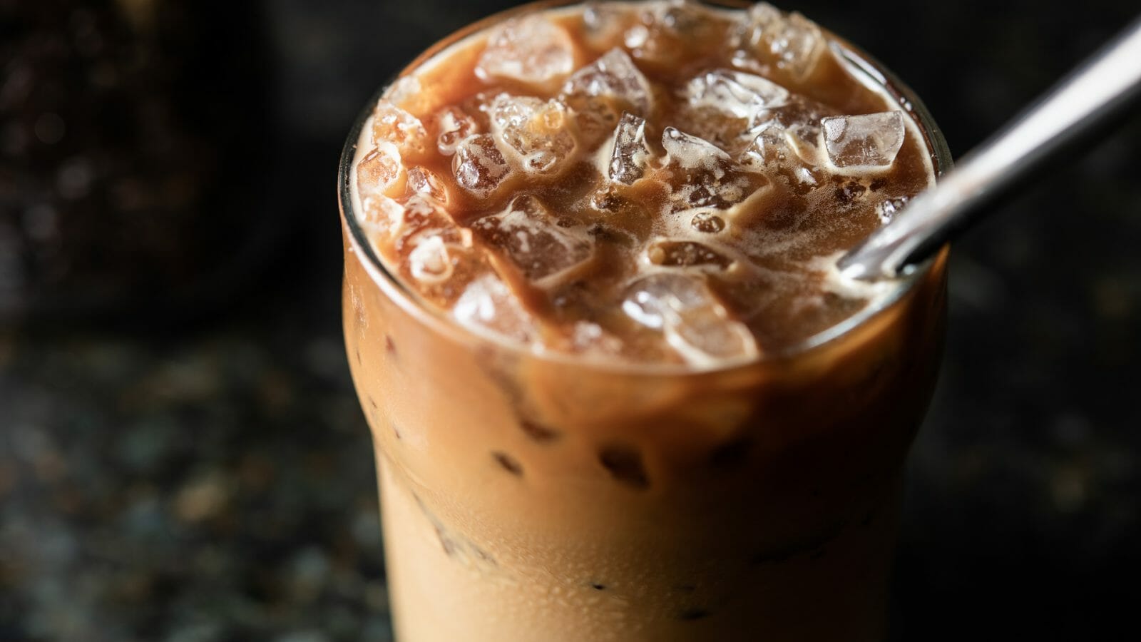tall glass of vietnamese iced coffee - strong dark coffee mixed with sweetened condensed milk, over ice